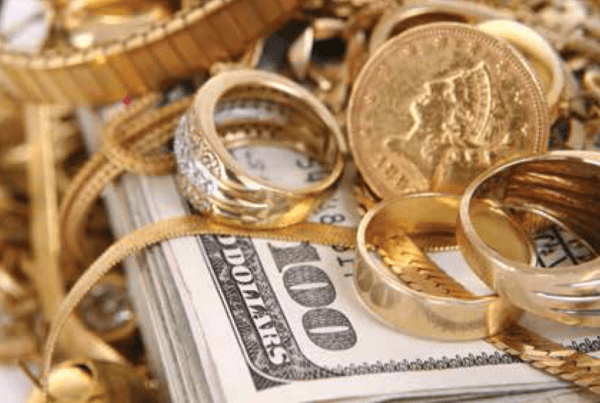 Gold jewelry and coins on cash stack at Ideal Jewelry and Loan pawn shop in Brockton, MA.