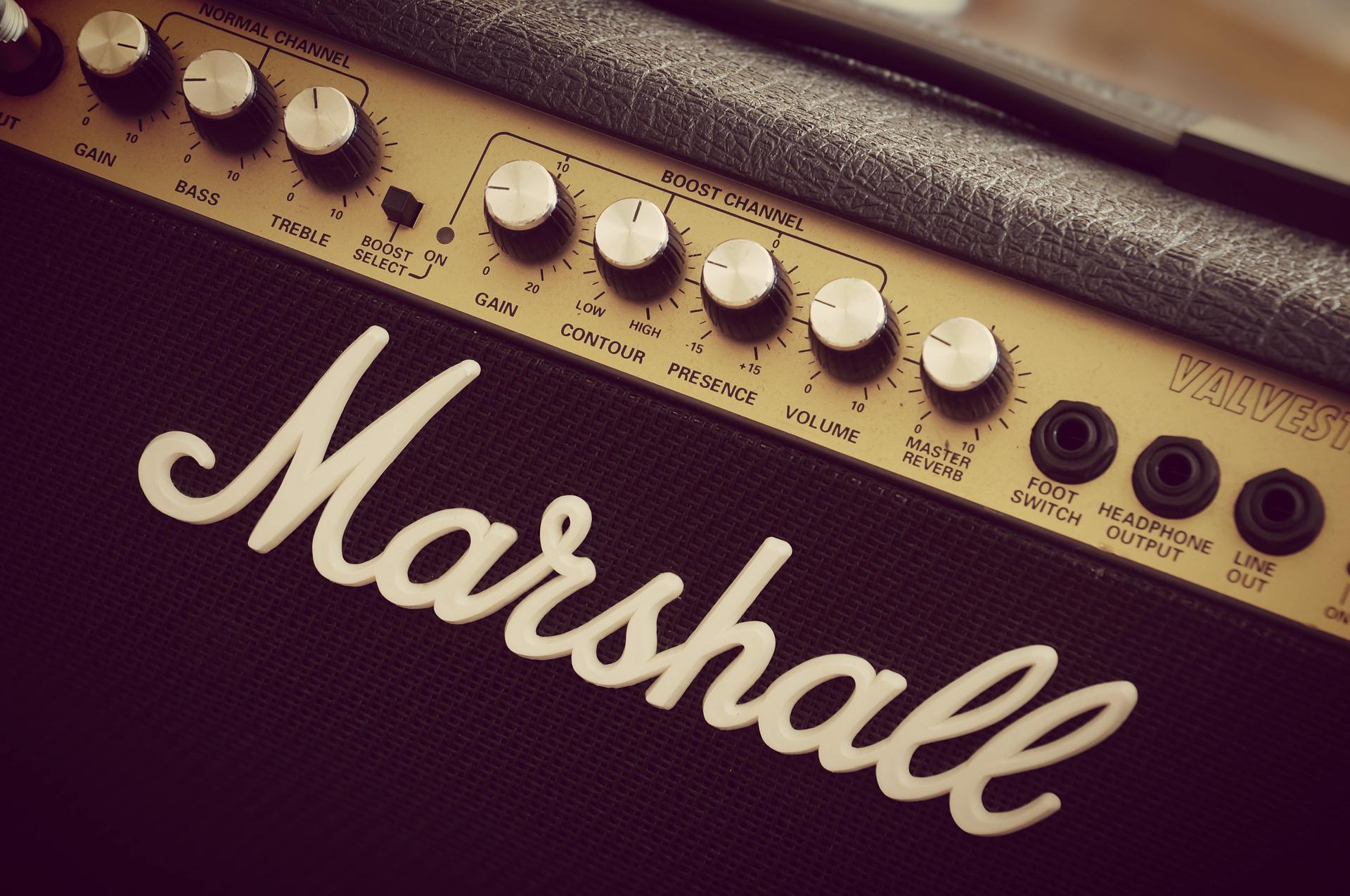 Close-up view of a Marshall guitar amplifier with labeled knobs and inputs for volume, gain, treble, bass, and reverb.