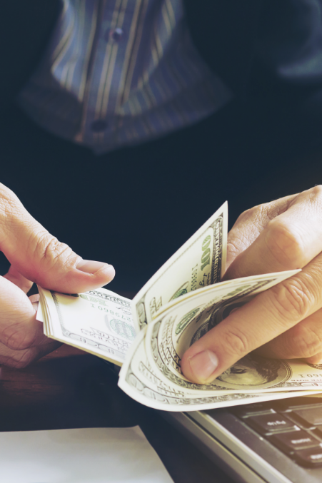 Person counting hundred-dollar bills after pawning an item at Ideal Jewelry and Loan pawn shop.