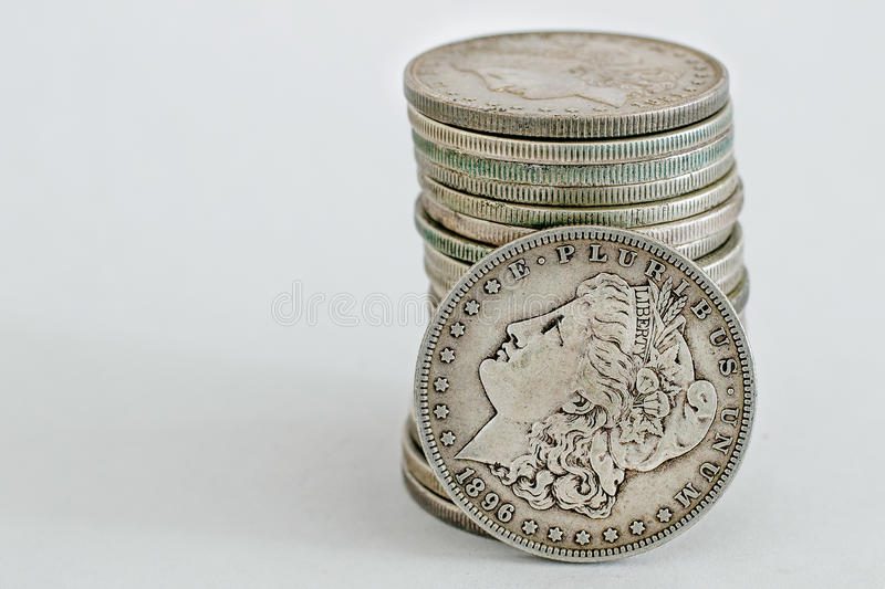 A stack of vintage Morgan silver dollar coins with the front coin dated 1896 showing Lady Liberty’s profile.