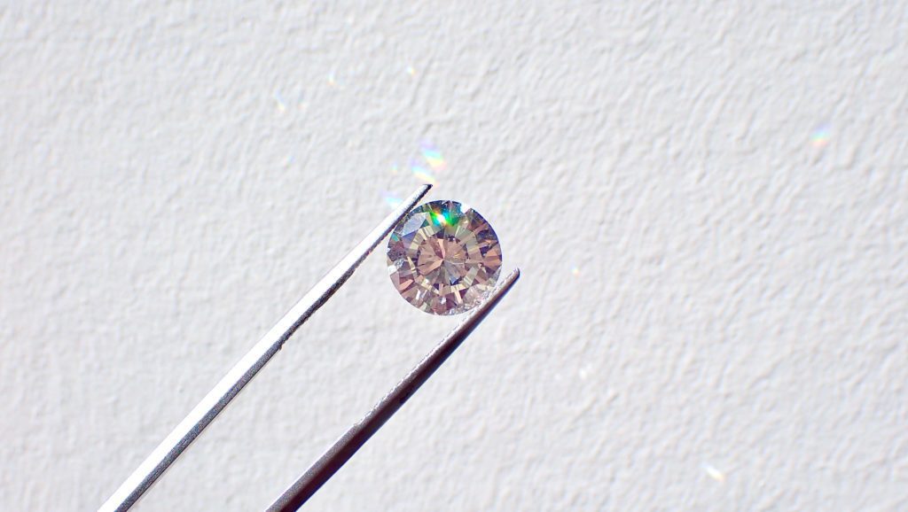Loose round diamond held by tweezers at Ideal Jewelry and Loan pawn shop in Brockton.