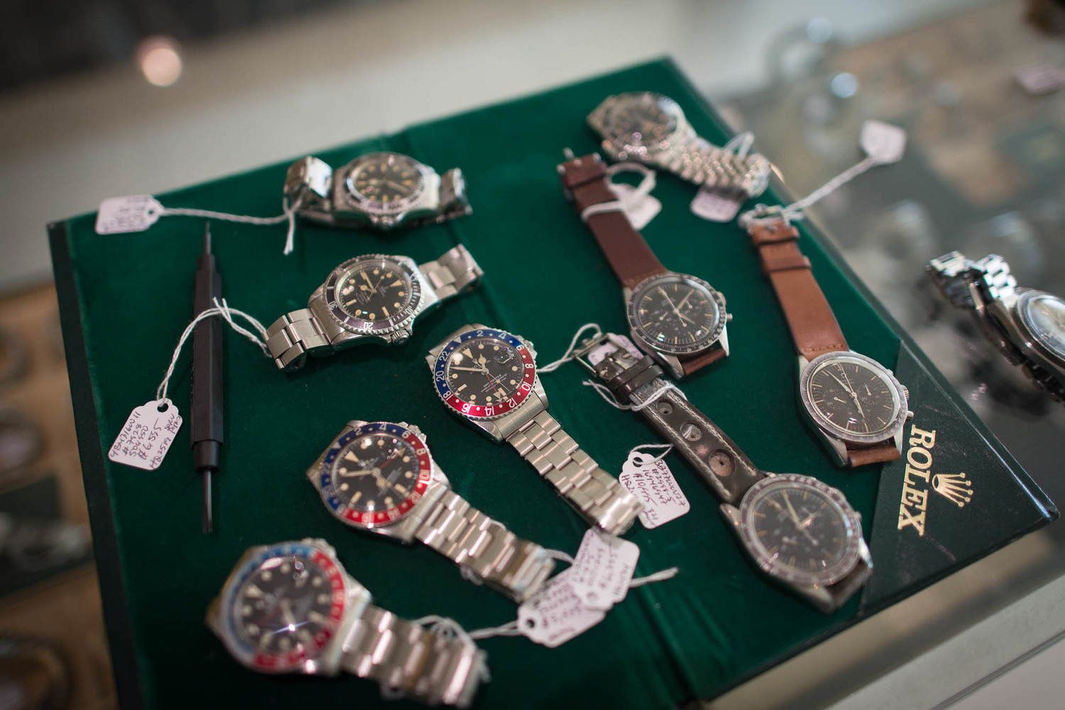 Assorted luxury watches displayed on a green Rolex case.
