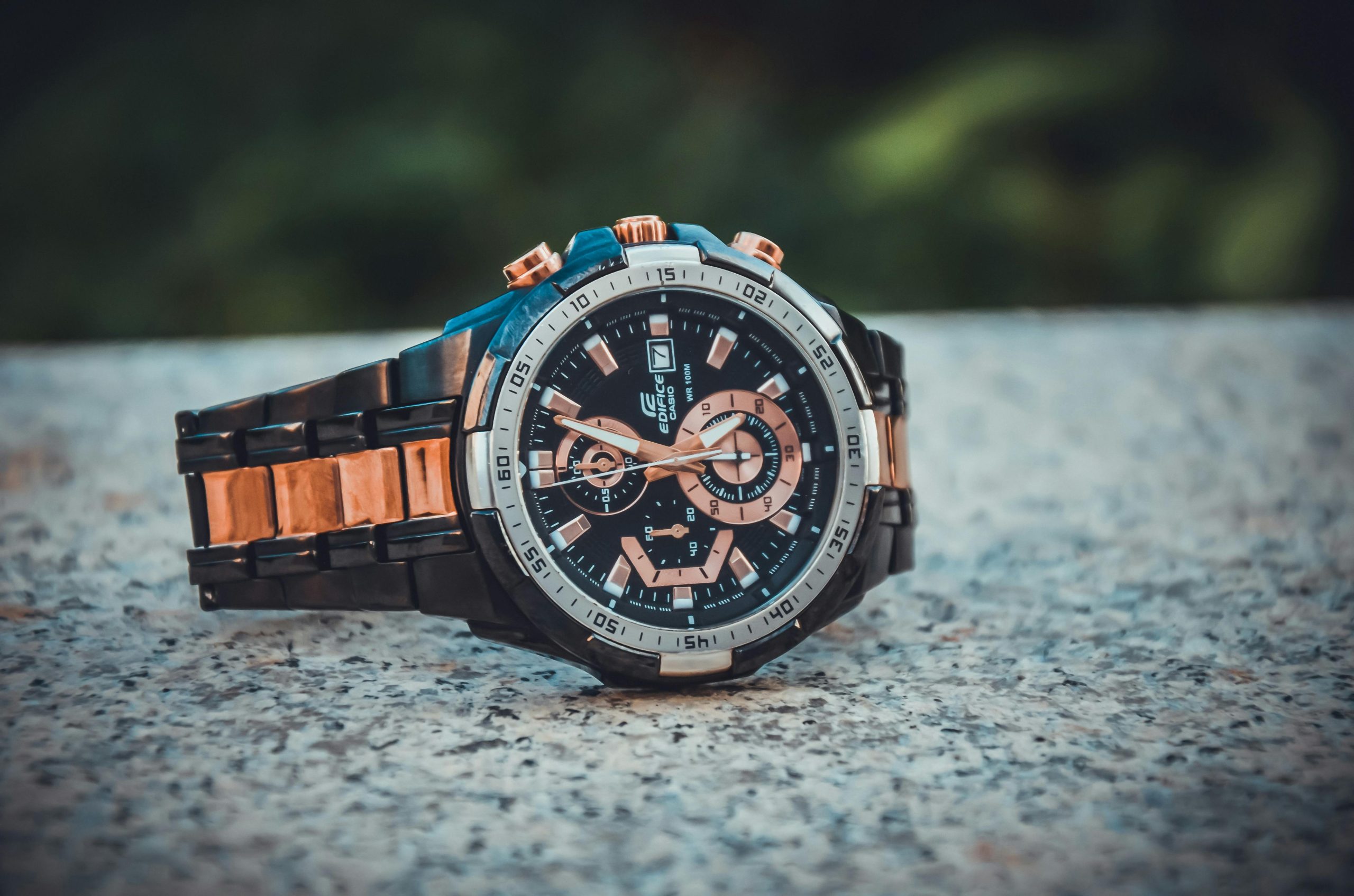 Luxury wristwatch with black and rose gold details on a granite surface.