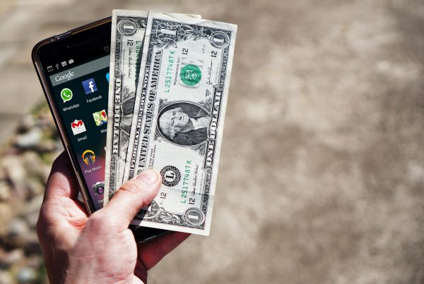 A hand holding cash and a smartphone symbolizing quick pawn shop transactions