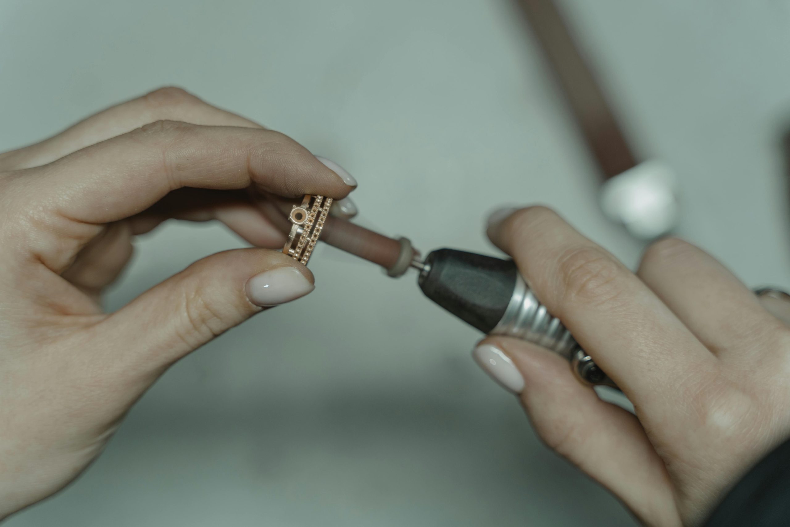 Close-up of hands polishing a piece of jewelry with a rotary tool