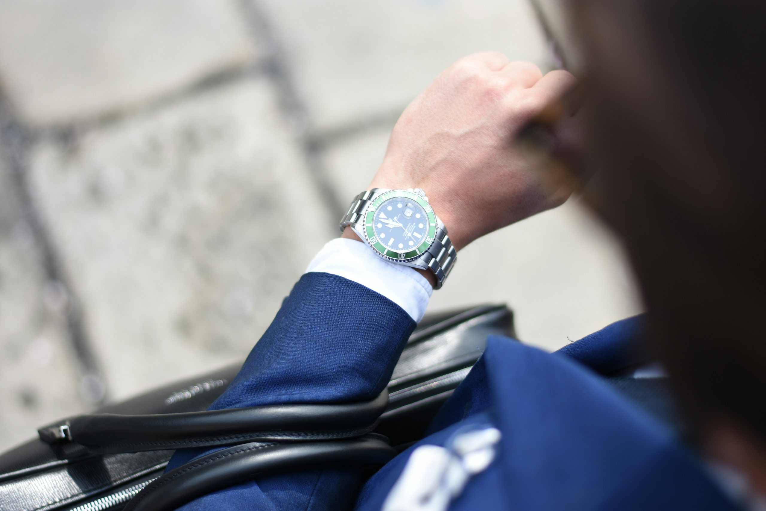 Close-up of a man in a blue suit checking time on a luxury silver wristwatch