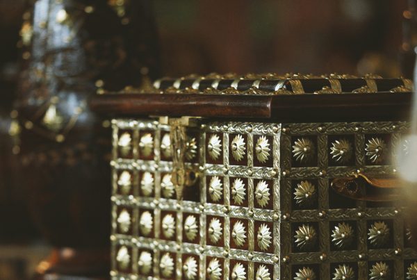 Ornate vintage jewelry box with intricate gold detailing on a wooden stump