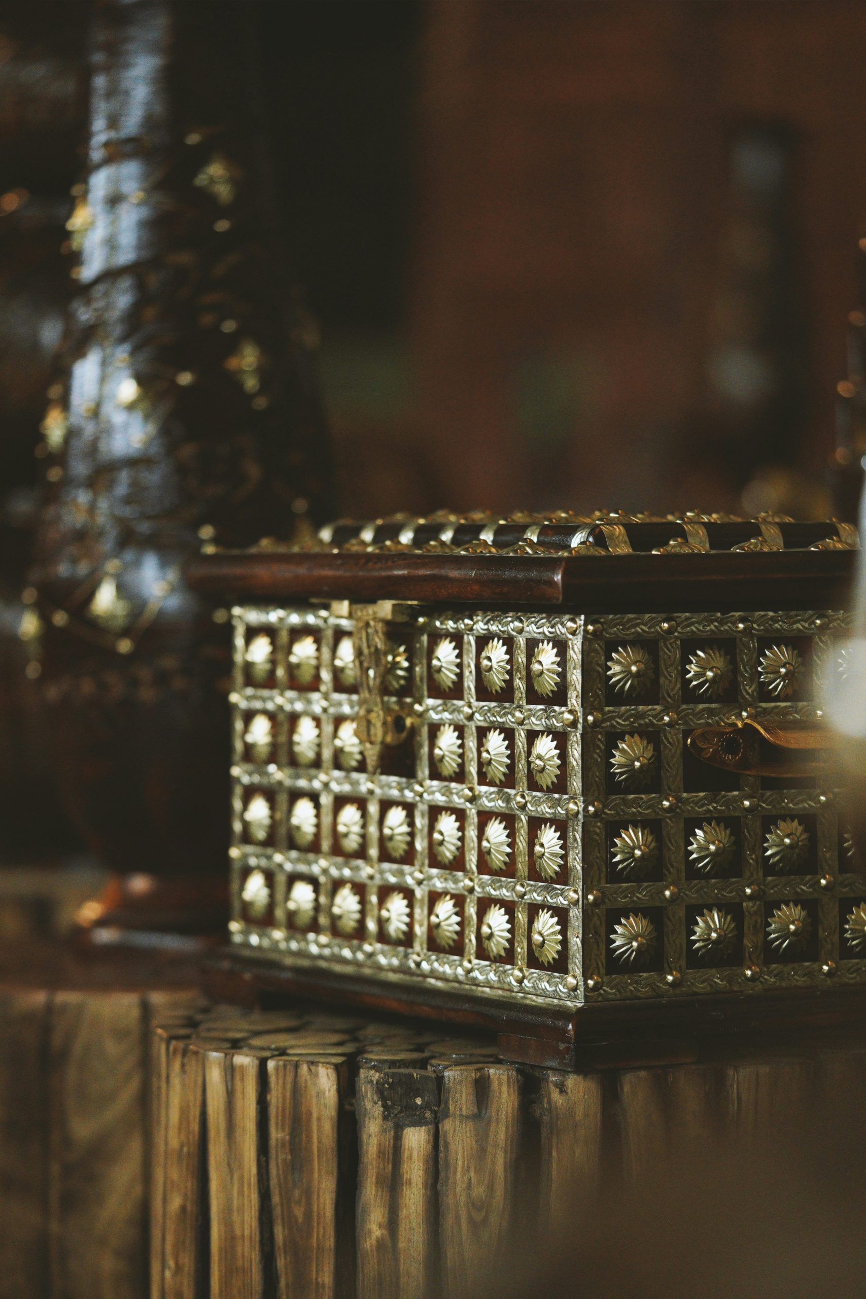 Ornate vintage jewelry box with intricate gold detailing on a wooden stump