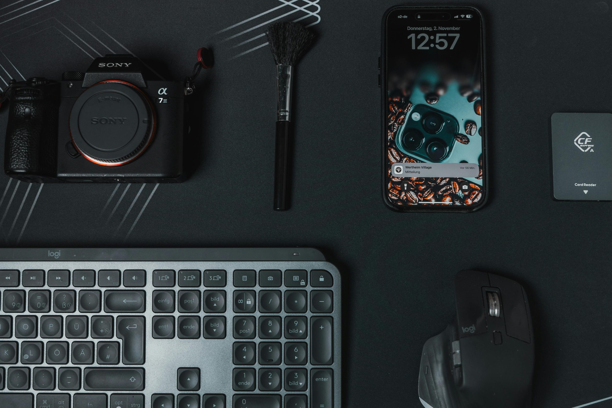 A DSLR camera, smartphone, keyboard, and accessories laid out on a dark surface, representing valuable electronics for pawn