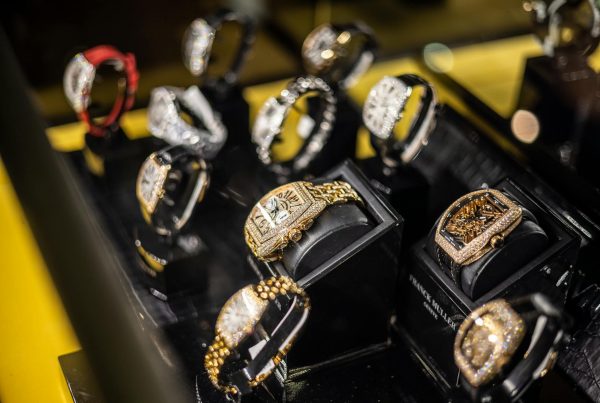 Luxury wristwatches displayed in a pawn shop showcase, including gold and diamond-encrusted designs