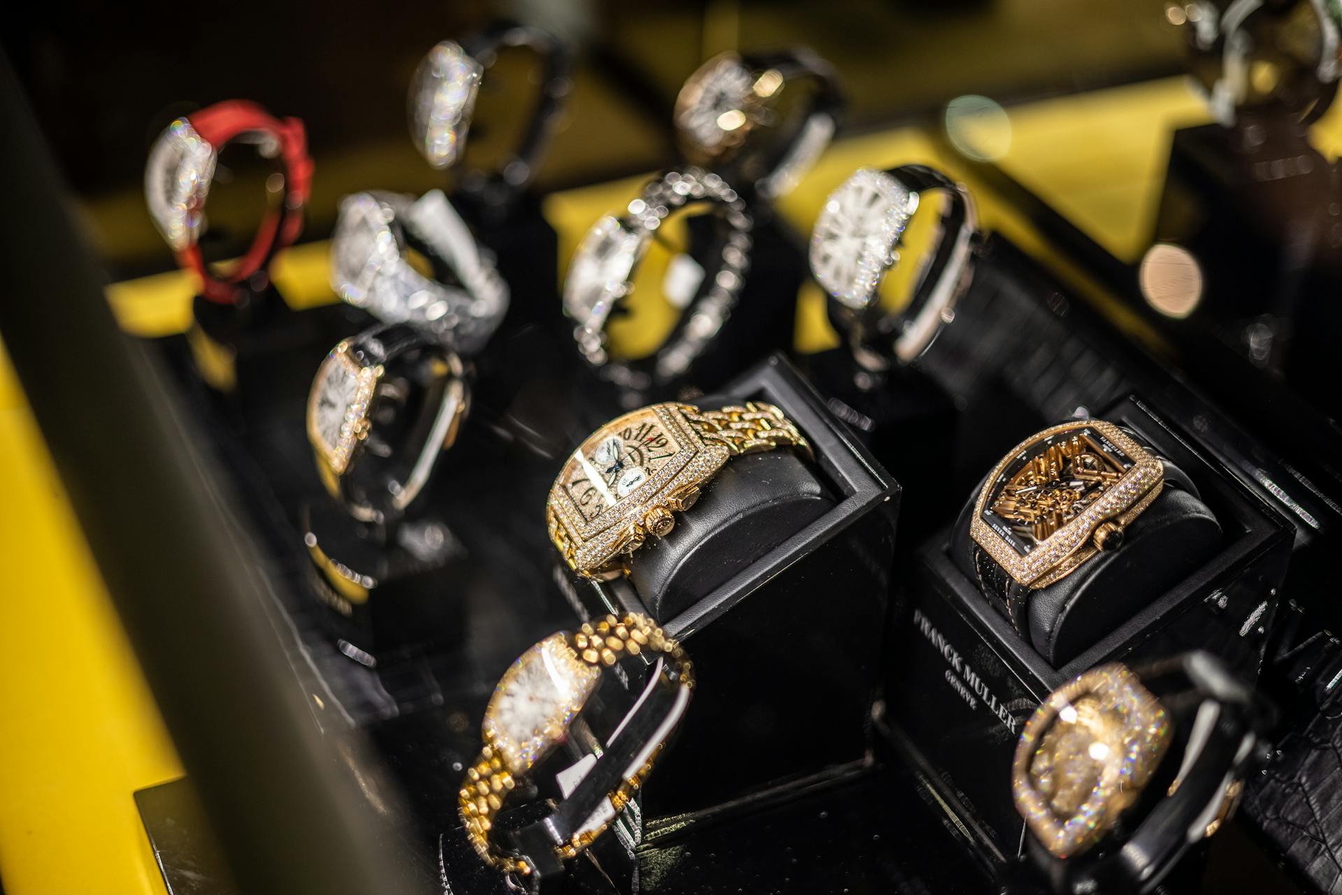 Luxury wristwatches displayed in a pawn shop showcase, including gold and diamond-encrusted designs