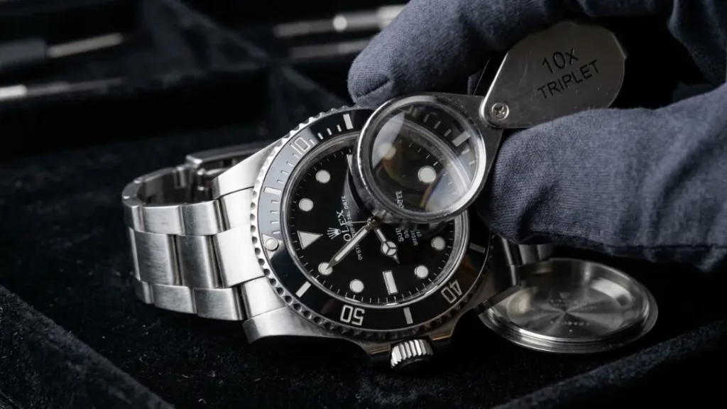 Jeweler inspecting a stainless steel Rolex Submariner watch on a velvet tray during a resale appraisal