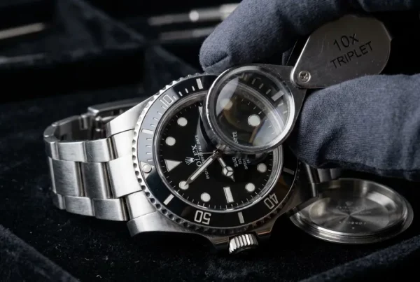 Jeweler inspecting a stainless steel Rolex Submariner watch on a velvet tray during a resale appraisal