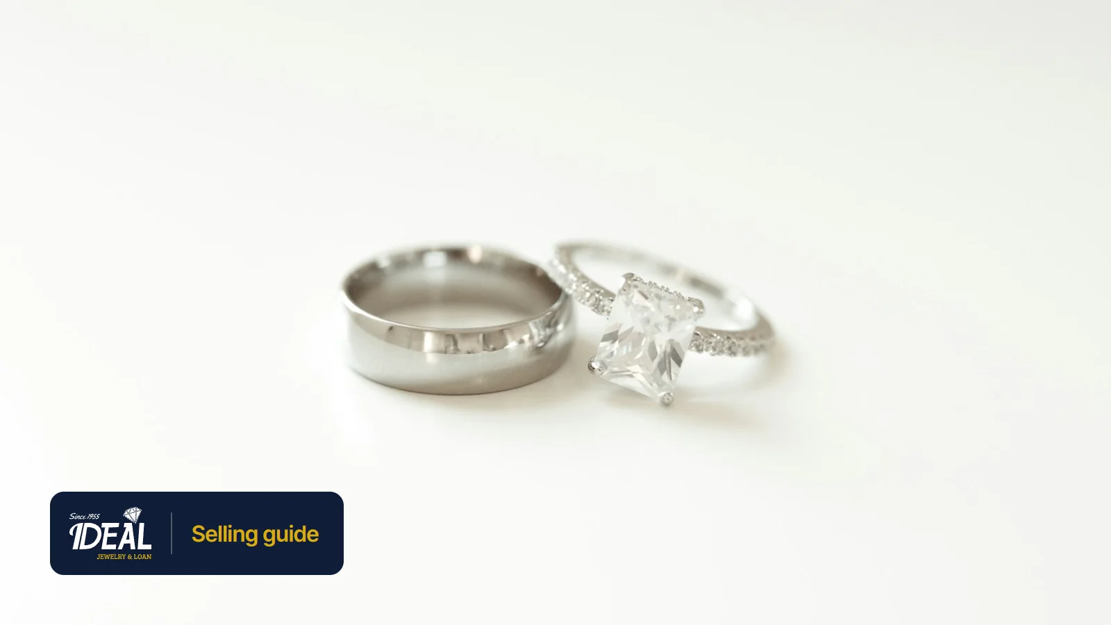 A plain wedding band beside a diamond engagement ring on a white surface